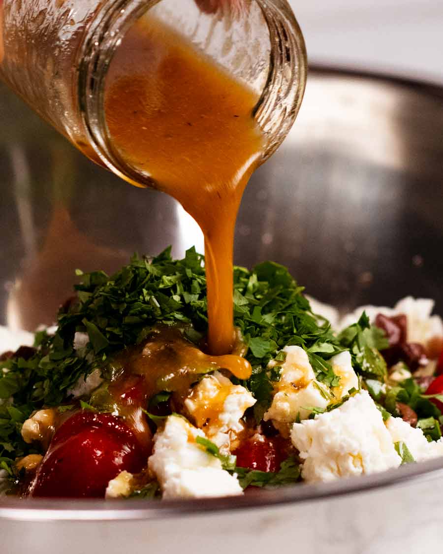 Pouring dressing over Antipasto chickpea salad