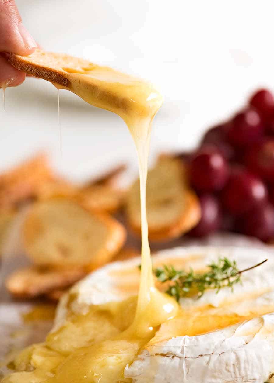 Crispy toasted bread scooping up Baked Brie