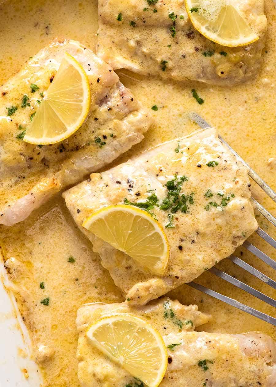 Overhead photo Baked Fish with Lemon Cream Sauce in a white baking dish, fresh out of the oven