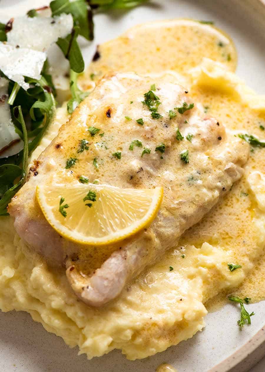 Overhead photo of Baked Fish with Lemon Cream Sauce on a plate with mashed potato and a side salad (rocket parmesan balsamic dressing)