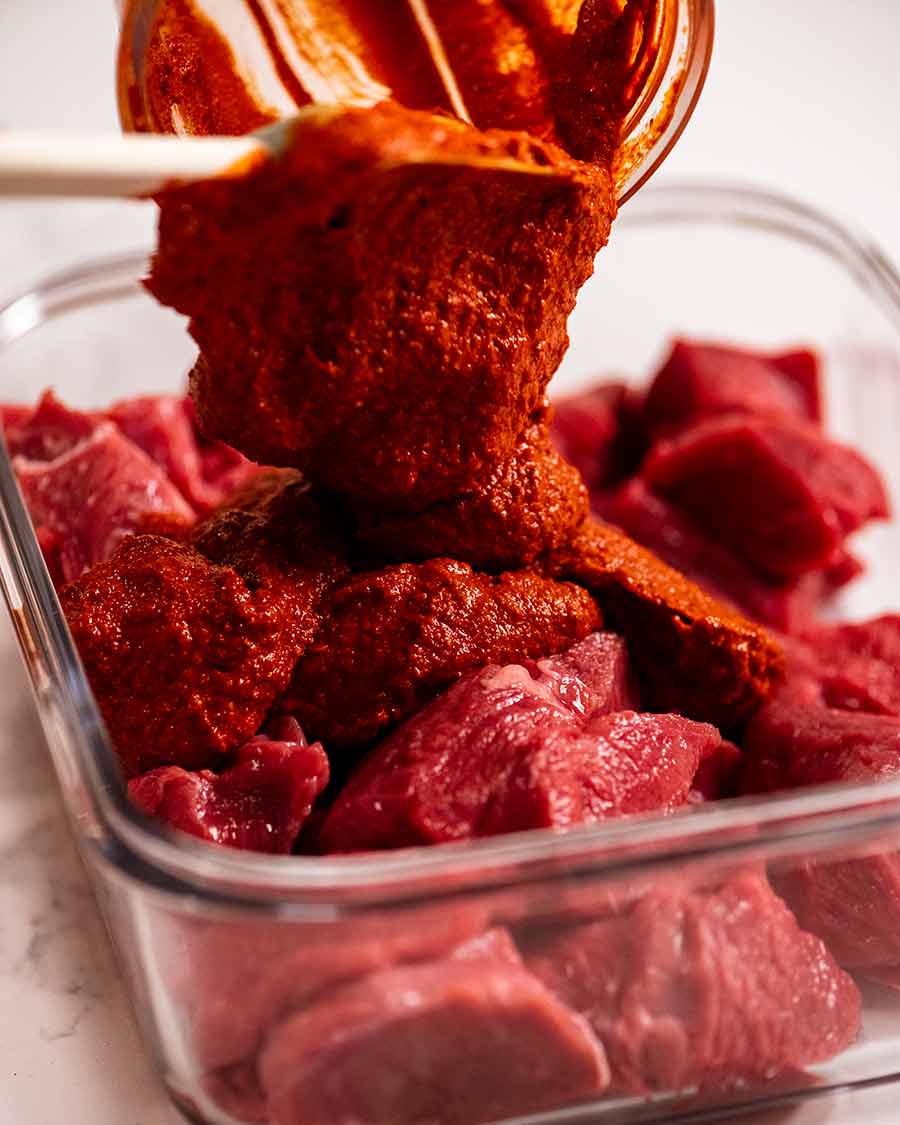 Pouring Vindaloo curry paste over beef to marinate