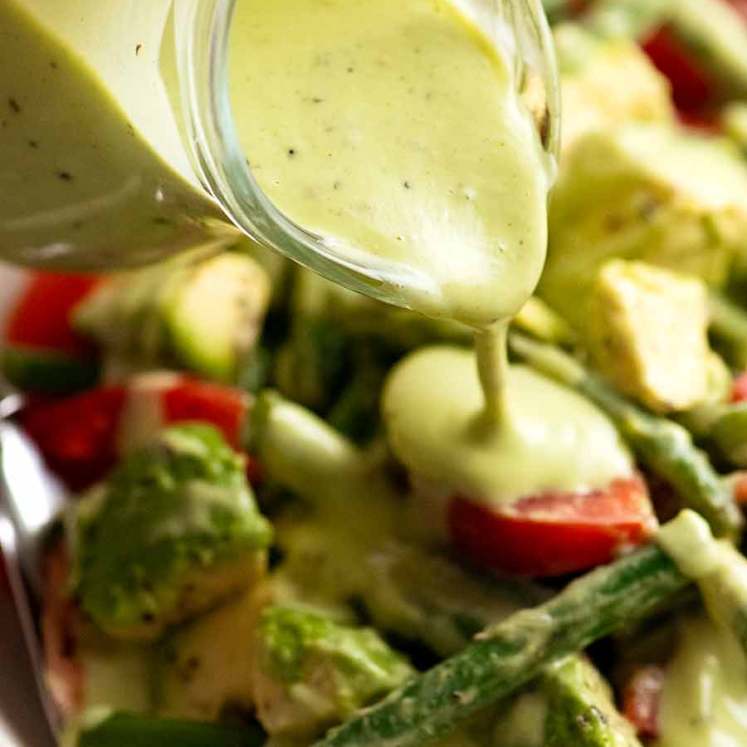 Pouring Creamy Avocado Dressing over green bean salad