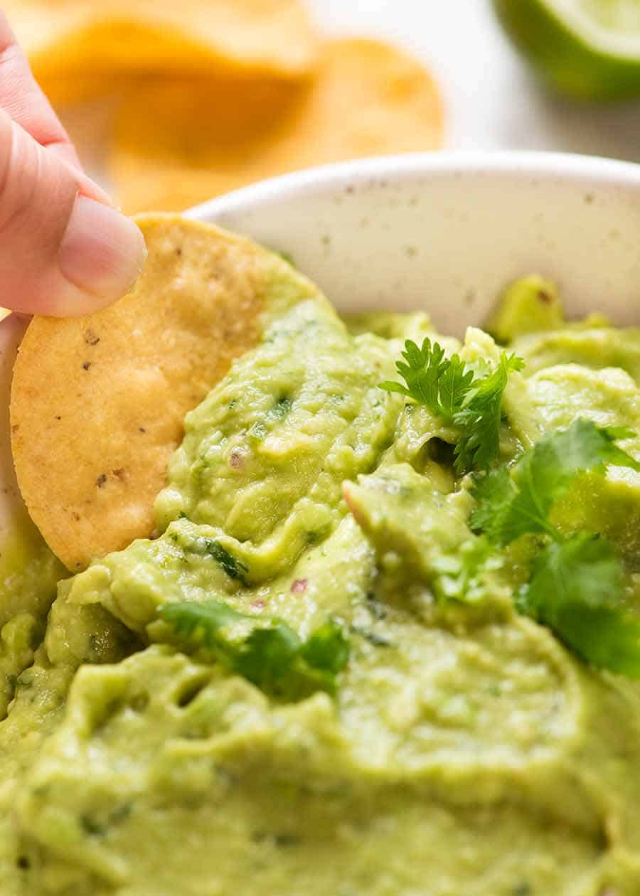 Close up of corn chip being dipped into Guacamole