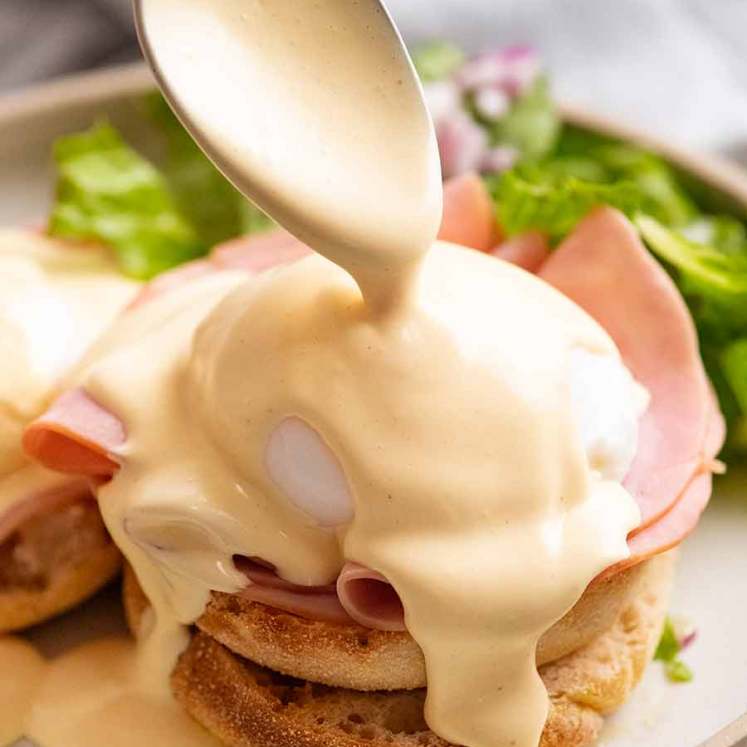 Pouring Hollandaise Sauce over Eggs Benedict