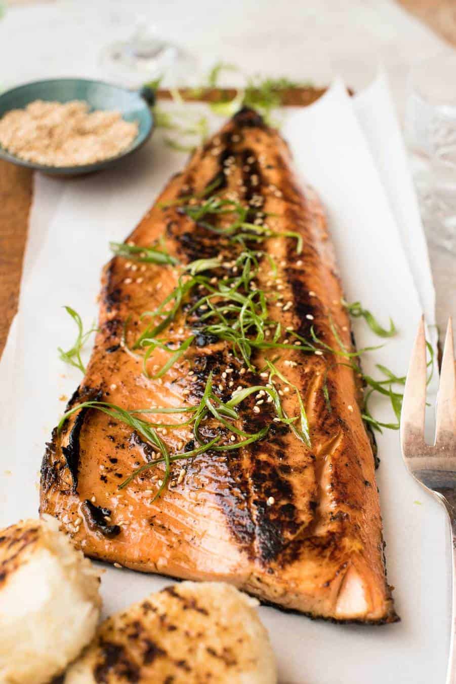 Japanese Miso Salmon Side on a wooden board garnished with steps of shallots / scallions, ready to be served.