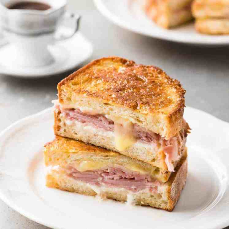 Monte Cristo Sandwich cut in half and stacked on each other on a small white plate, ready to be eaten.