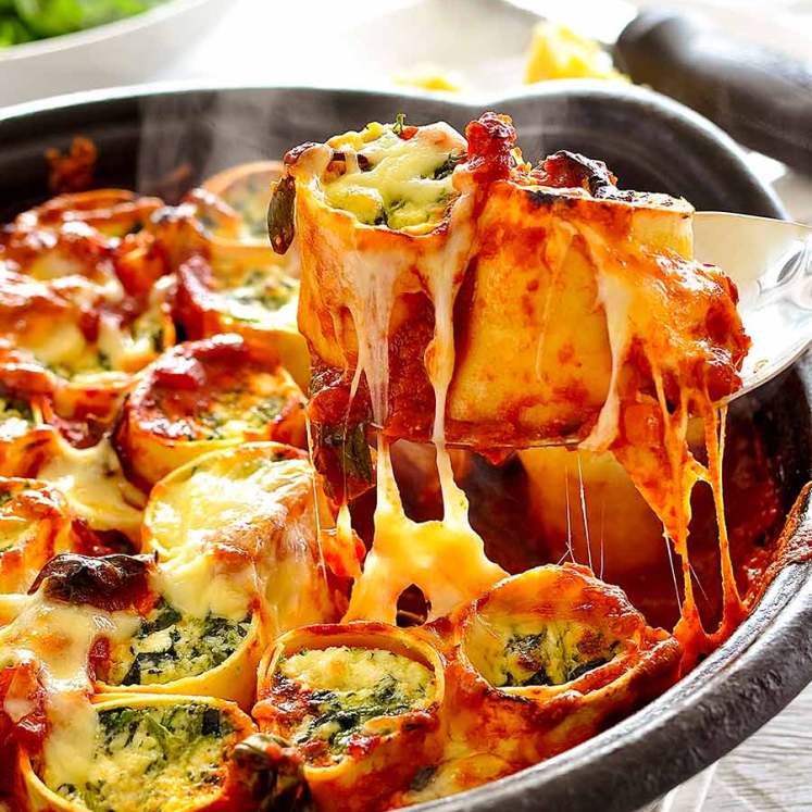 Spoon lifting up Spinach and Ricotta Rotolo - cheese pull!